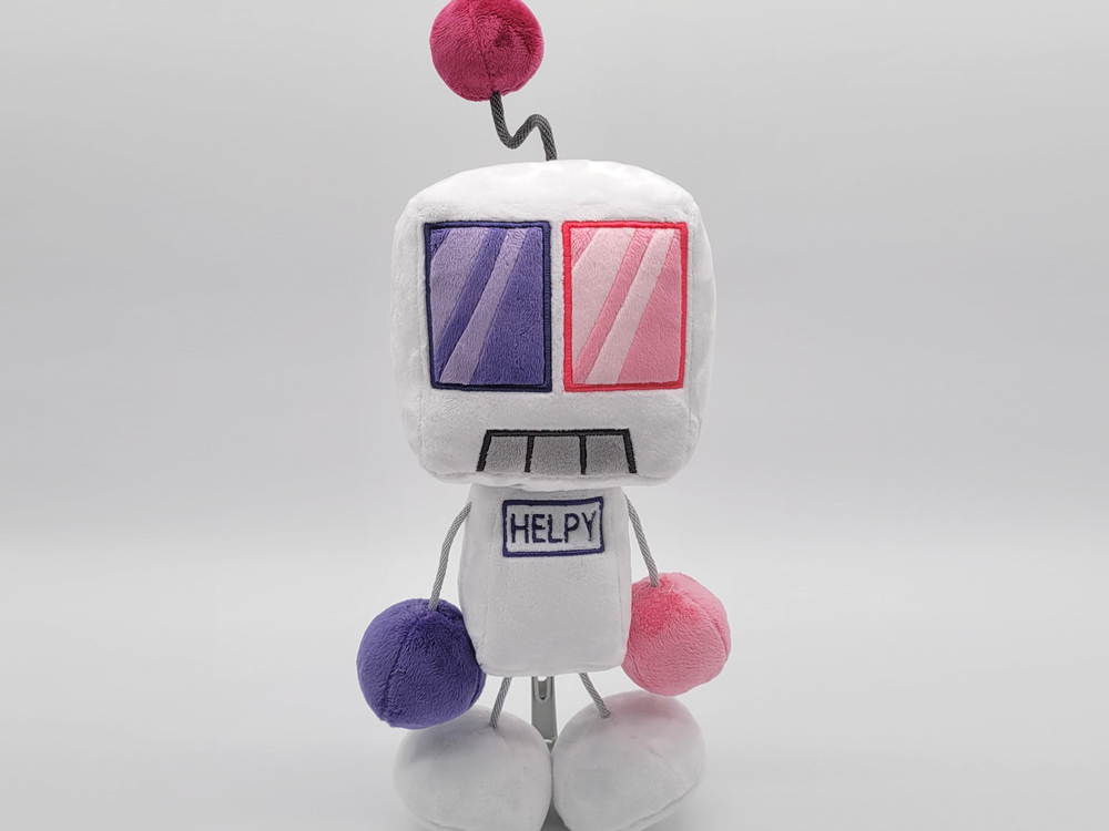 A white robot plushie. It's body is a verticle rectangle, and it's head is a large cube. It has one purple eye and hand, and one pink eye and hand. It's hands and feet are attached with grey string, and there is a maroon ball held above it's head like an antenna with a wired string.